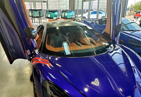 Blue exotic sports car with doors open getting a new windshield